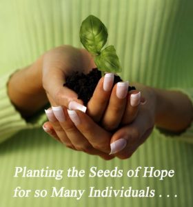 woman of color in green shirt holding a seedling in